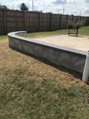 Backyard patio with bordering decorative stone wall
